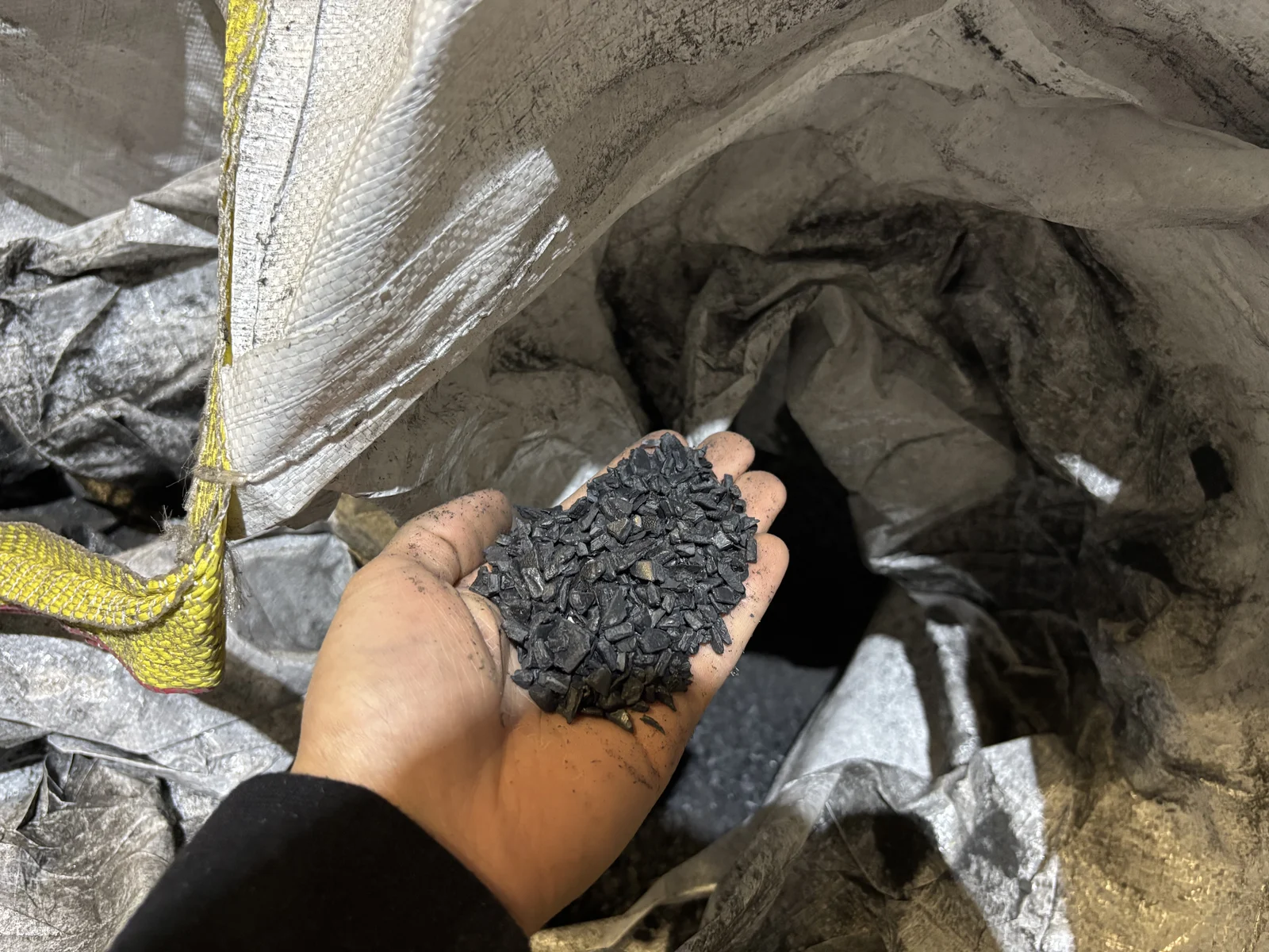 A handful of polypropylene regrind inside a bulk storage bag